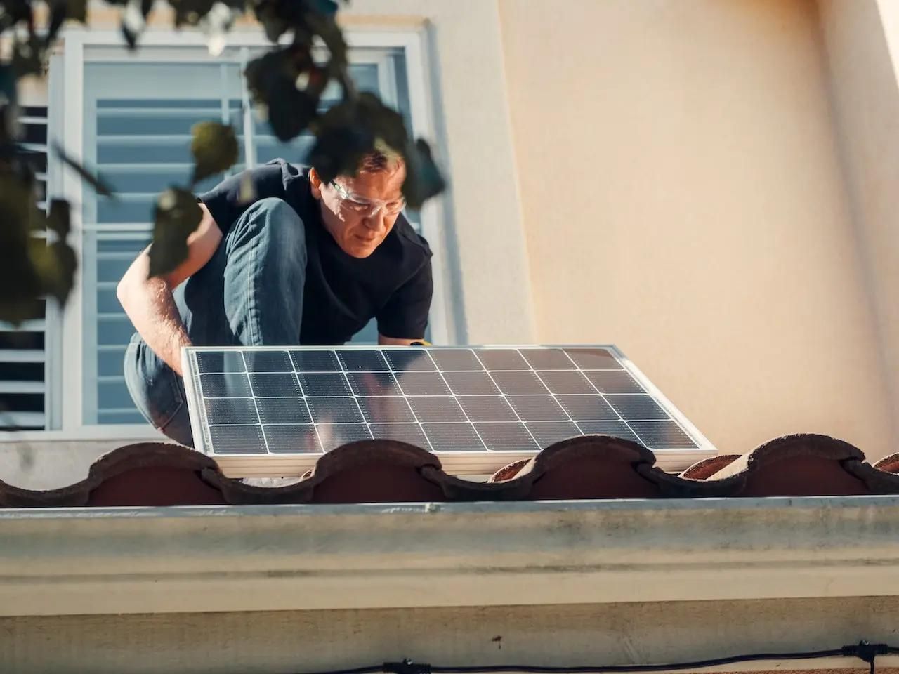 Ein Solarmodule wird von einem Handwerker auf einem Dach montiert.