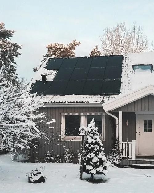 Haus mit Solarmodule auf dem Dach und Garten im Schnee